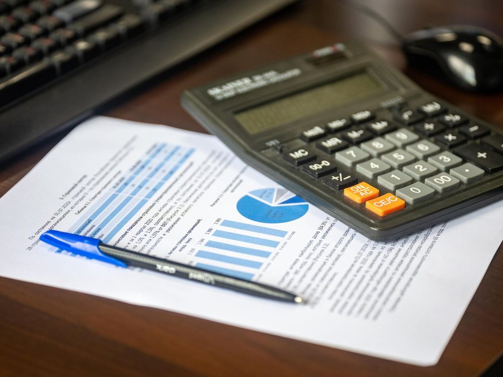 A laptop and printed data charts on a desk